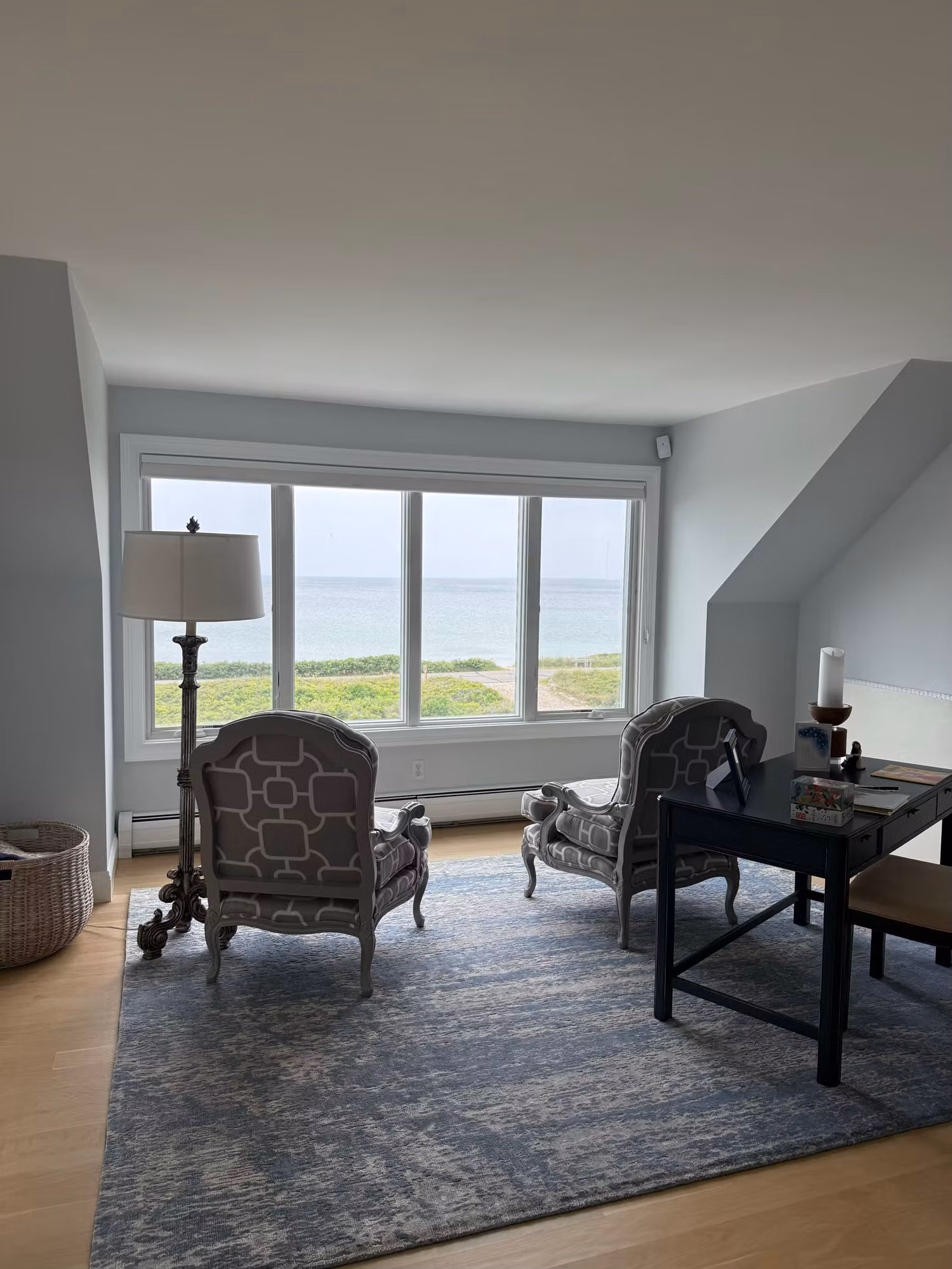 Sitting room with a wide picture window of clear film framing an unobstructed ocean view.