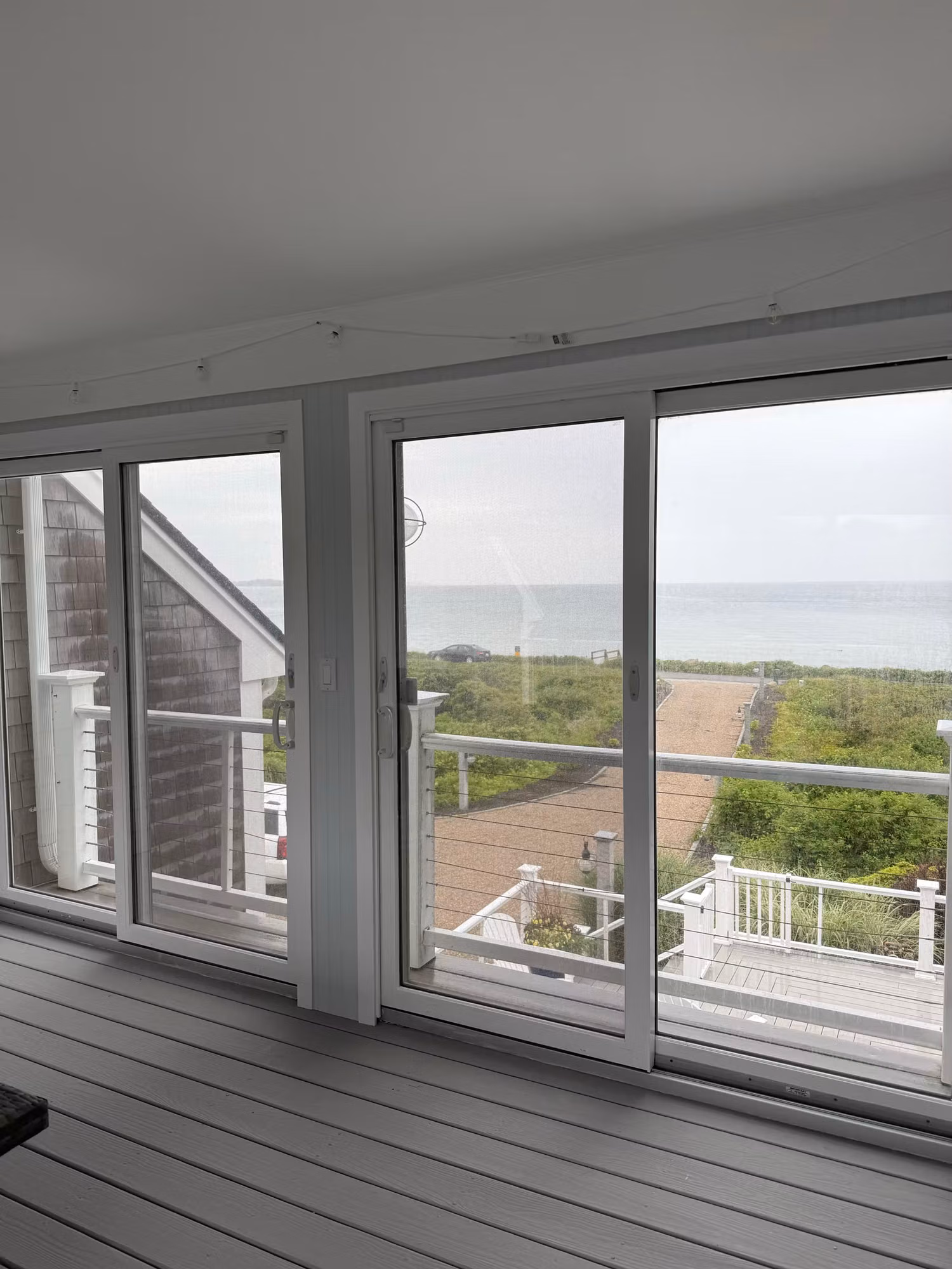 Large sliding glass doors in a coastal living space framing an ocean and deck view.