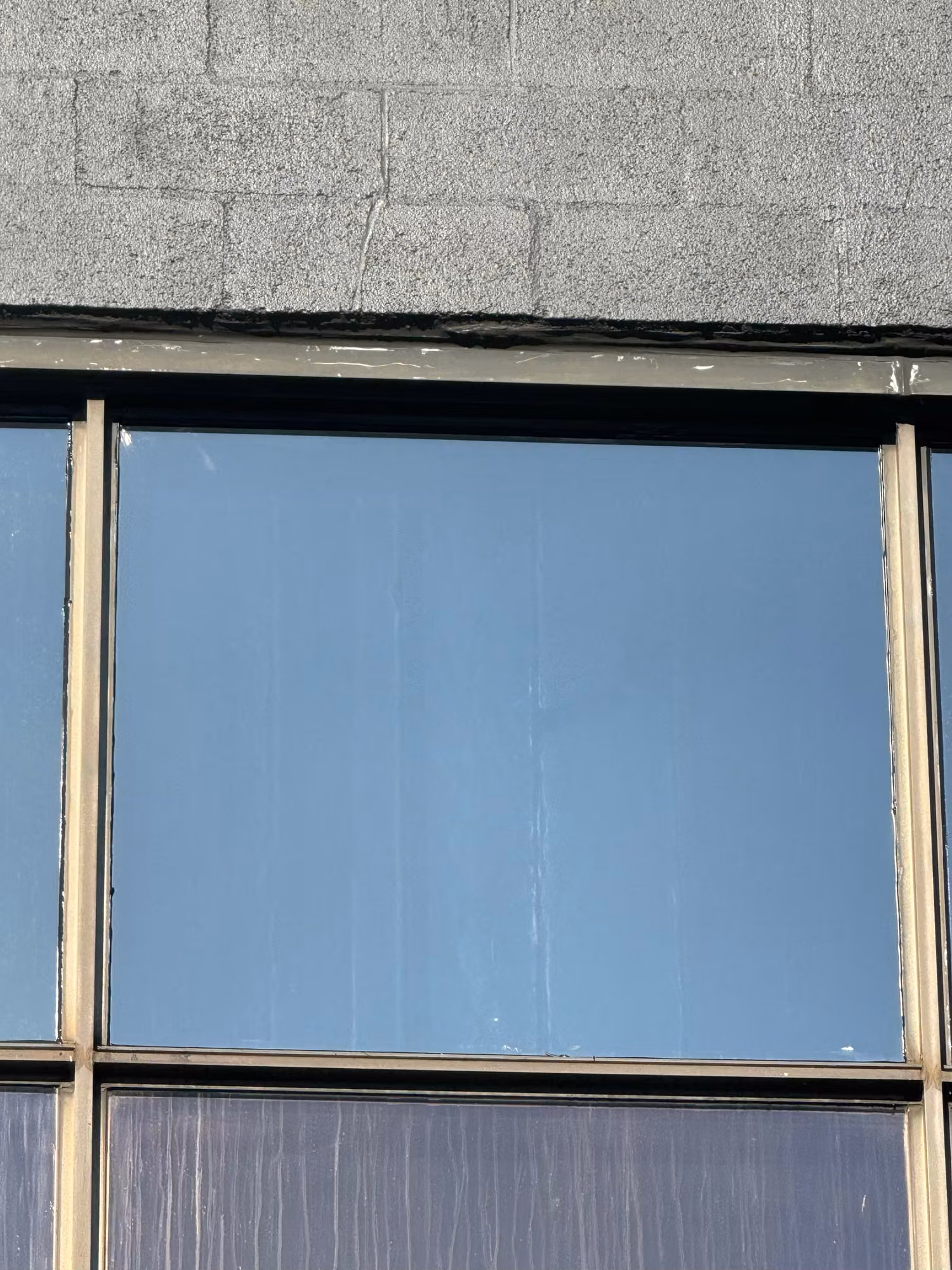 Exterior view of a cinderblock building window glazed with a reflective solar control film reducing heat and glare.