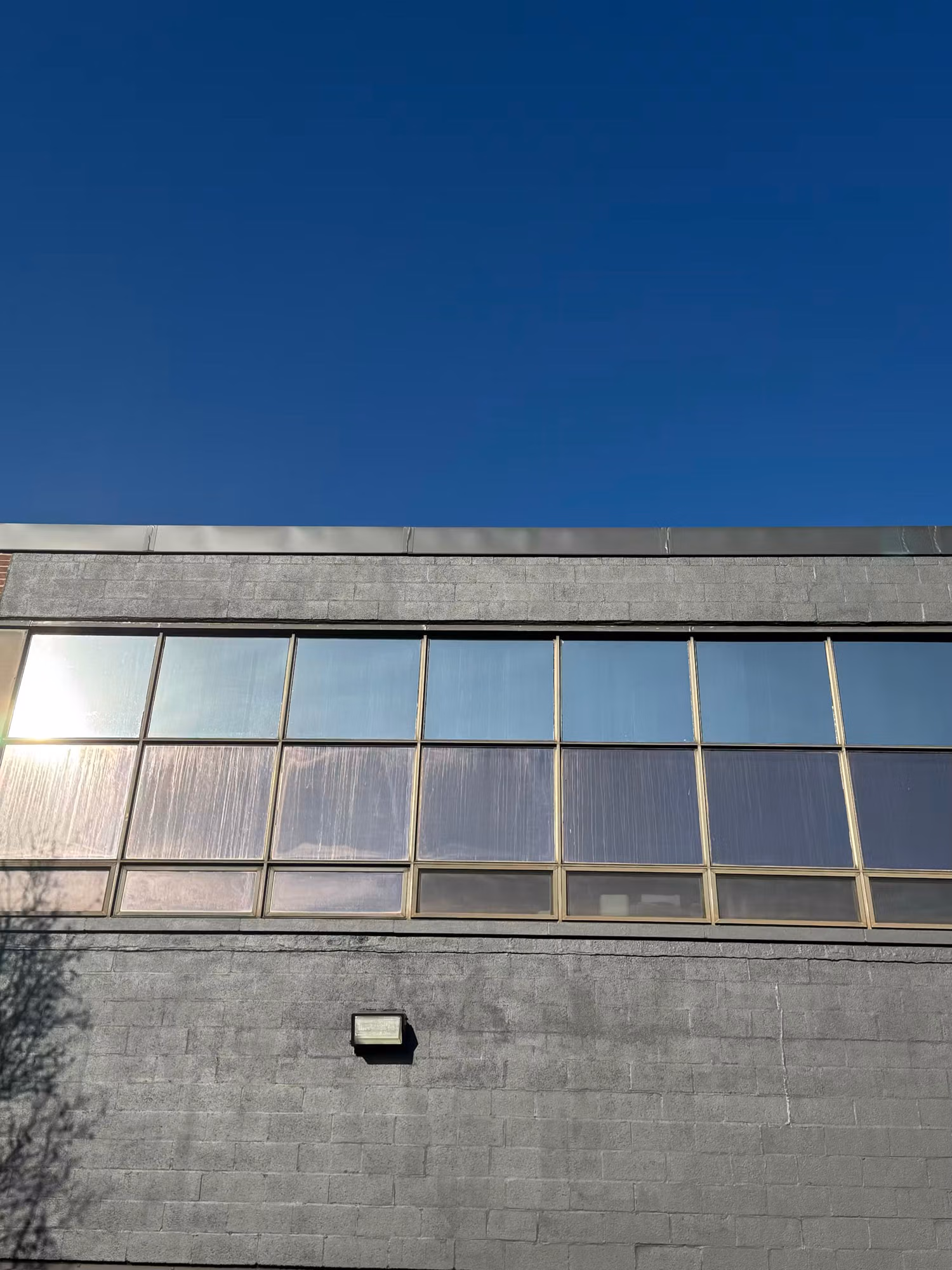 Upper window band on a concrete-block building with reflective solar control film catching the daylight.