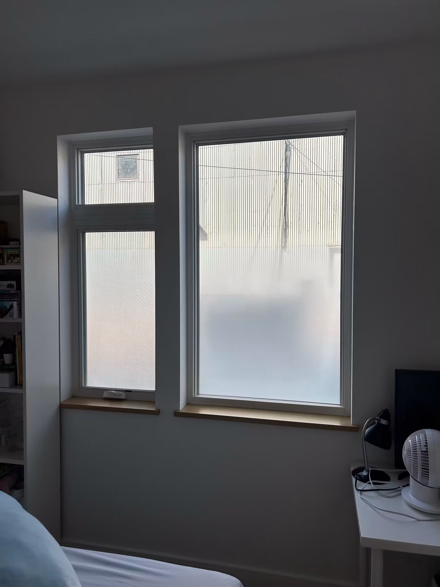 Bedroom windows with frosted privacy film across the lower panes leaving the upper sections clear for light.