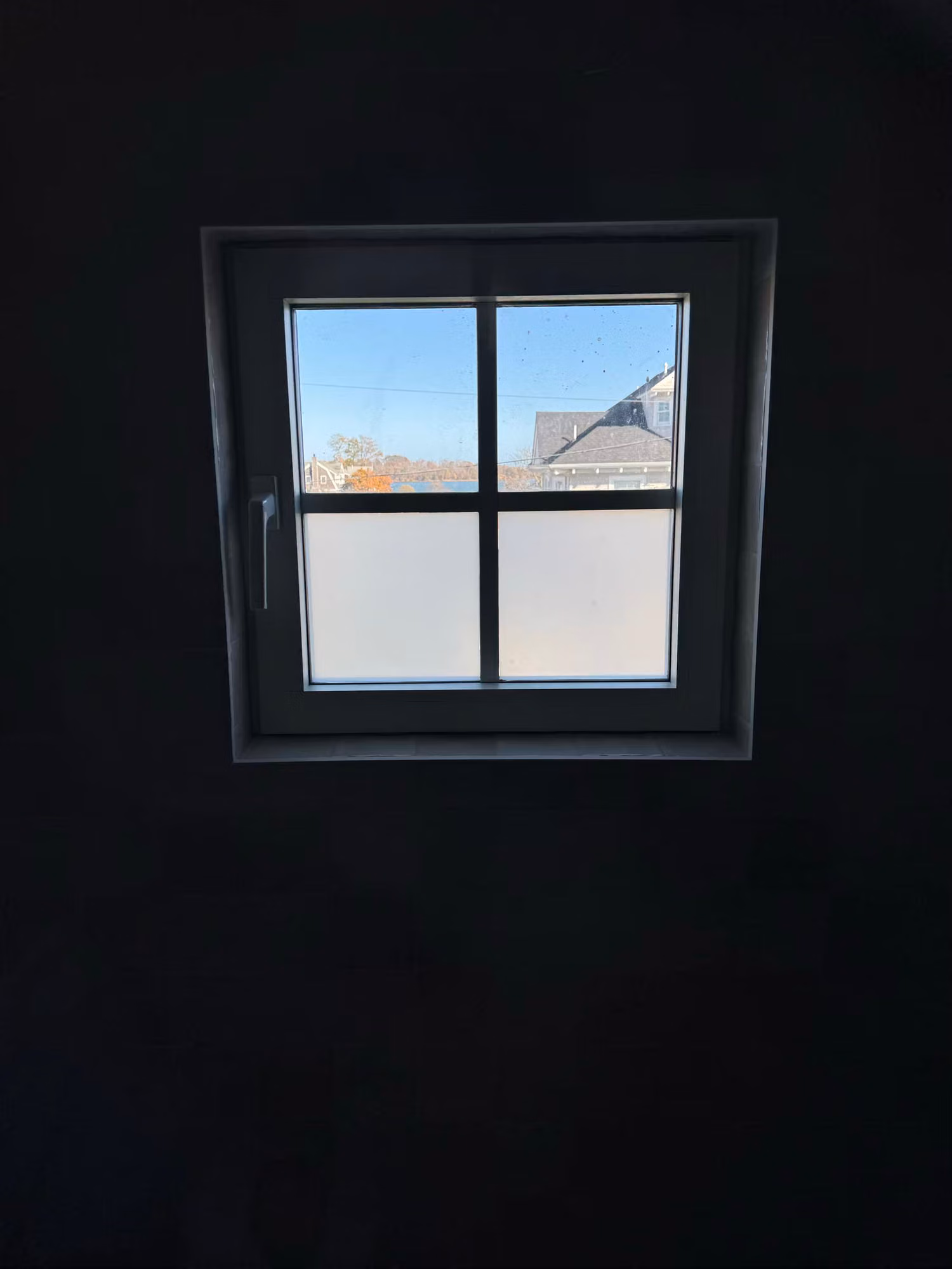 Small divided-light window with frosted privacy film on the lower panes while the upper panes stay clear.