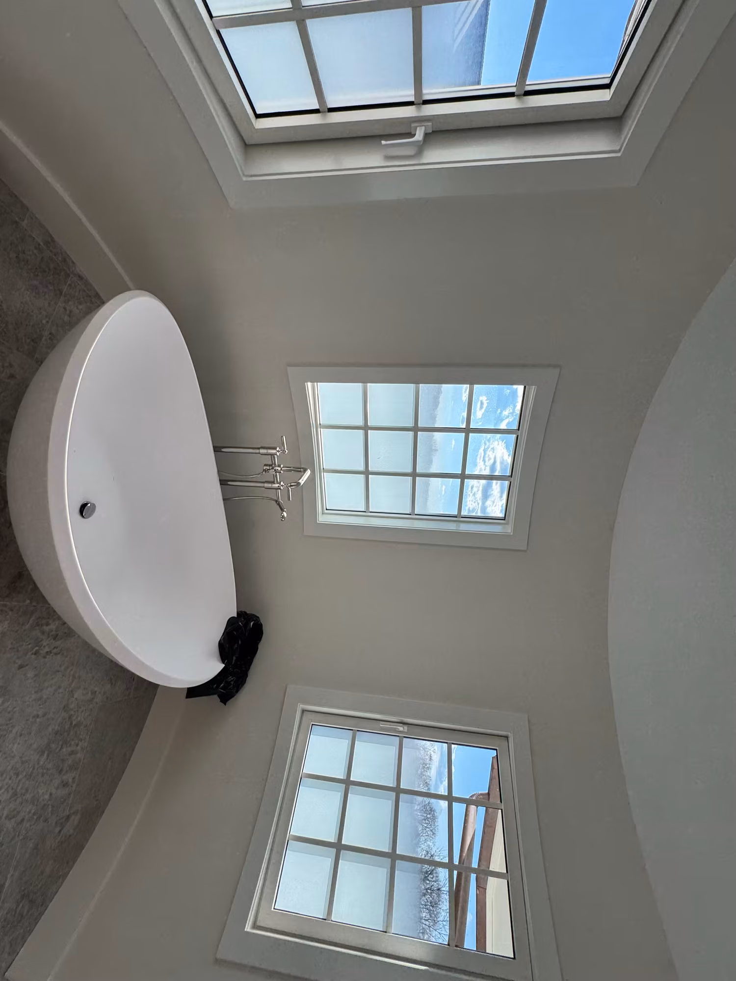 Bathroom windows with frosted privacy film on the lower panes beside a freestanding tub and skylight.