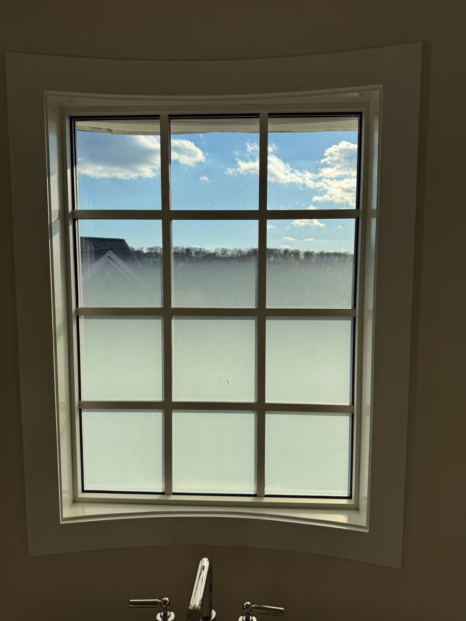 Grid window above a soaking tub with frosted privacy film on the lower panes while the upper panes stay clear.
