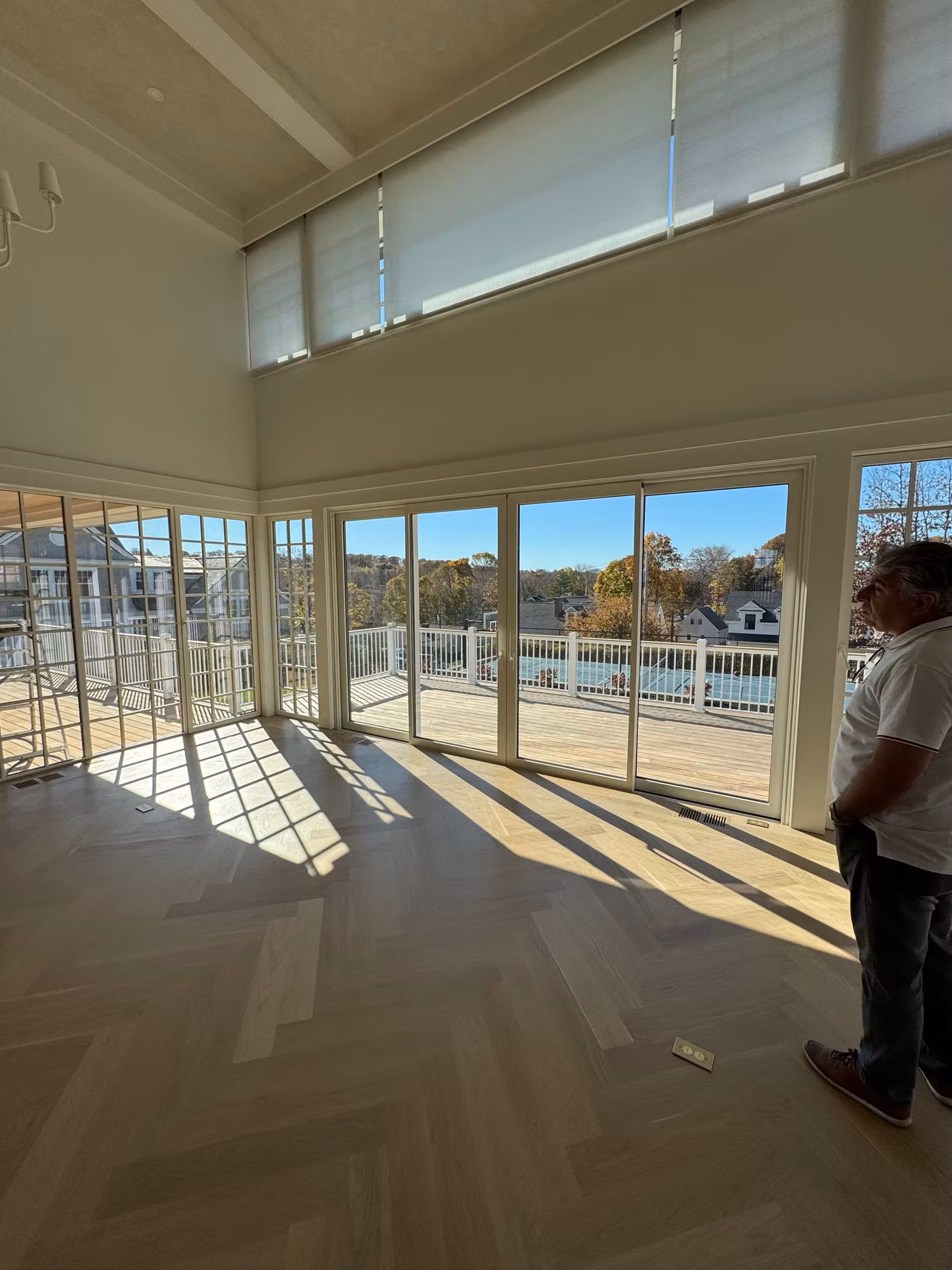 Bright living room with a wall of sliding glass doors and transom windows opening onto a deck with water views.