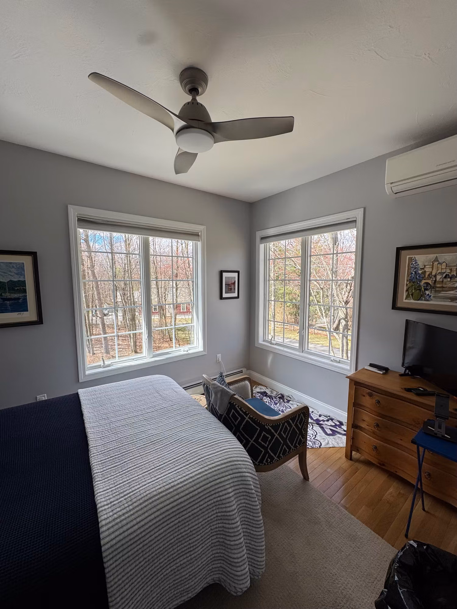 Bright bedroom with two large windows treated with clear solar control film, keeping the wooded view while cutting heat and UV.