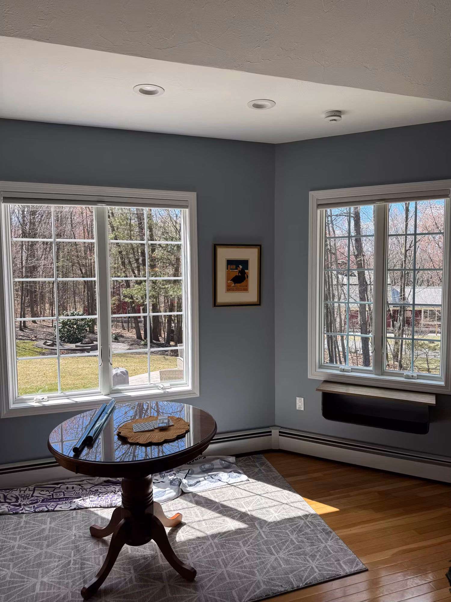 Corner dining nook with two banks of windows treated with clear solar control film, preserving the backyard view in bright daylight.
