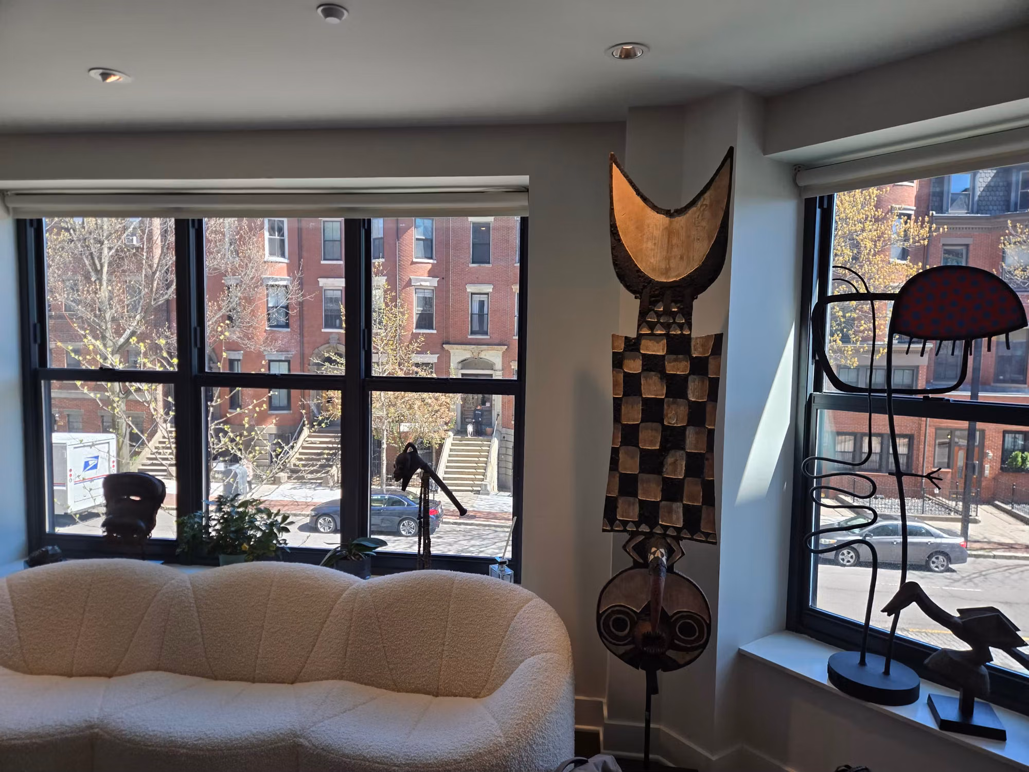 Living room with three-panel and single black-framed picture windows treated with film, over a townhouse street.