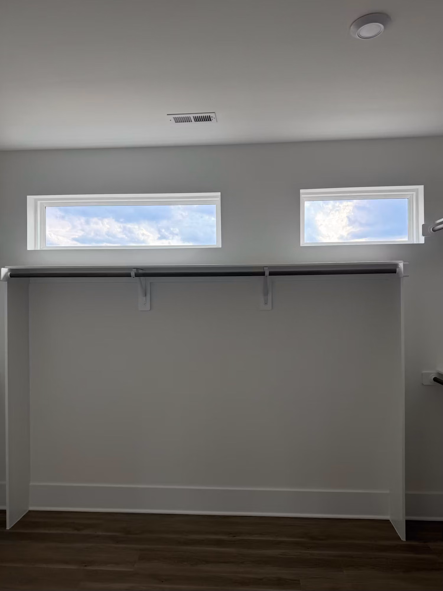Two high transom windows above a walk-in closet shelf, letting in bright sky light.