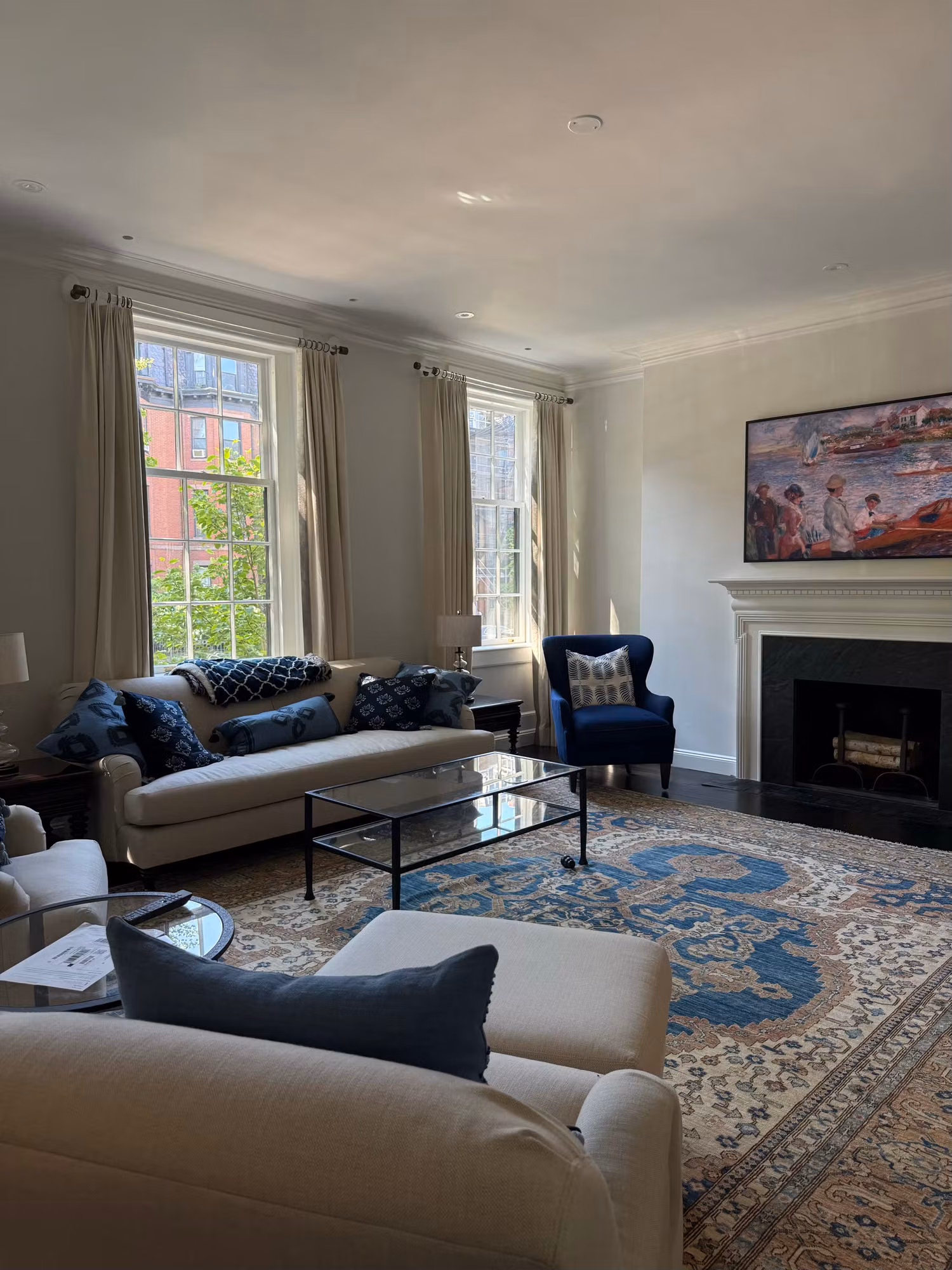 Living room with two tall divided-light windows beside a fireplace and patterned area rug.