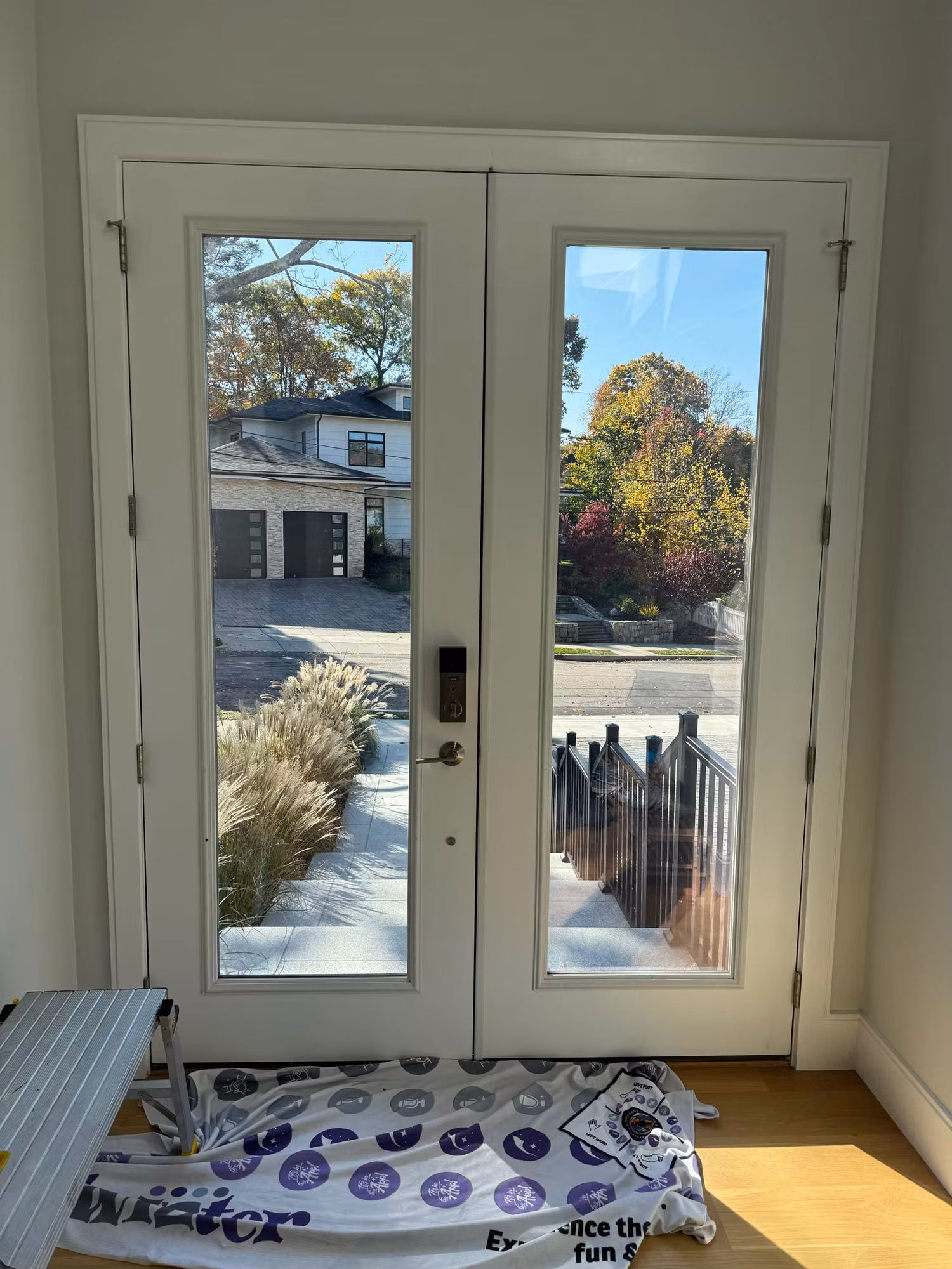 Clear glass French entry doors before privacy film, with packaging laid out on the floor for install.