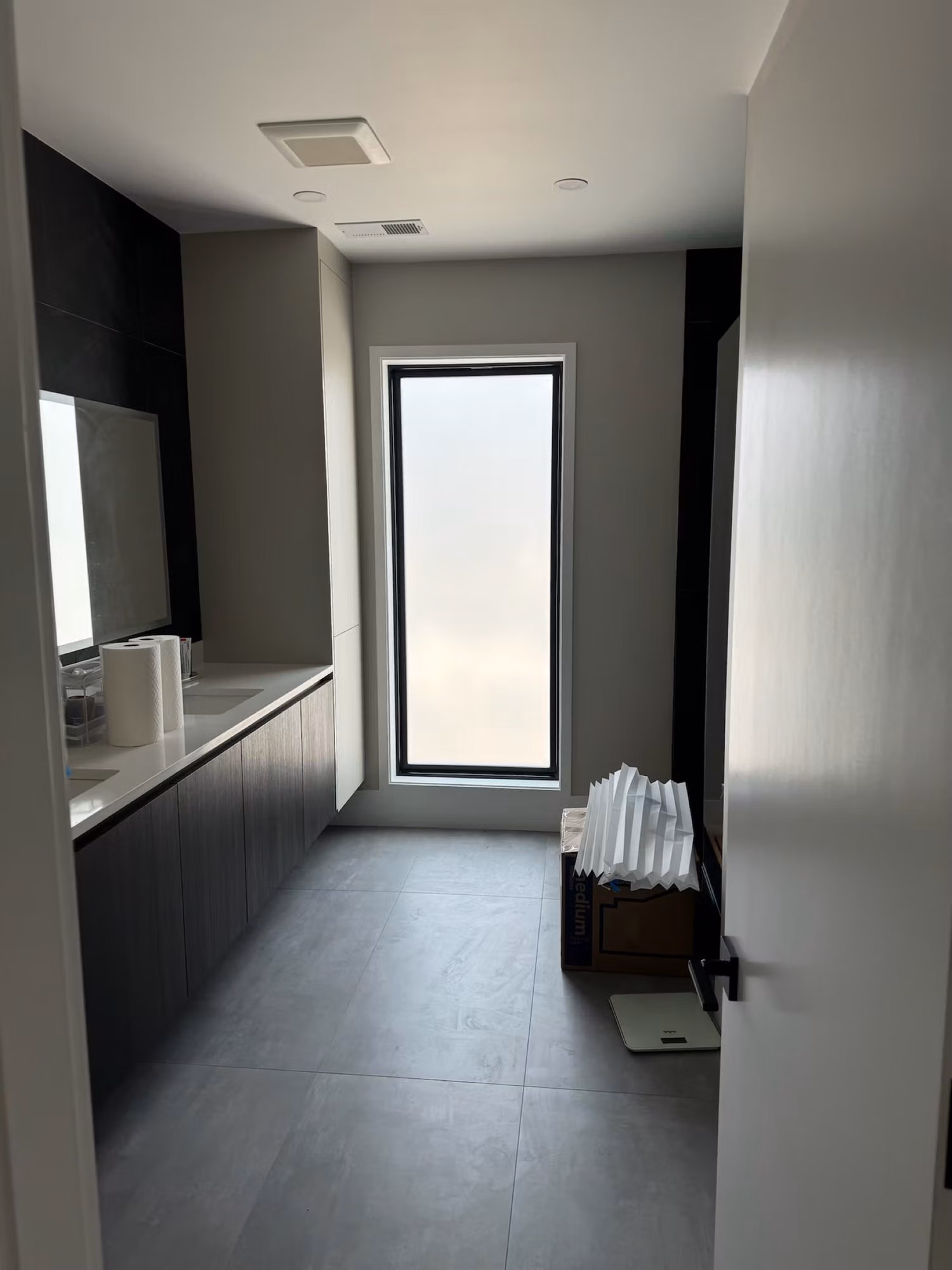 Tall narrow bathroom vanity window finished with white frosted privacy film for soft diffused light.
