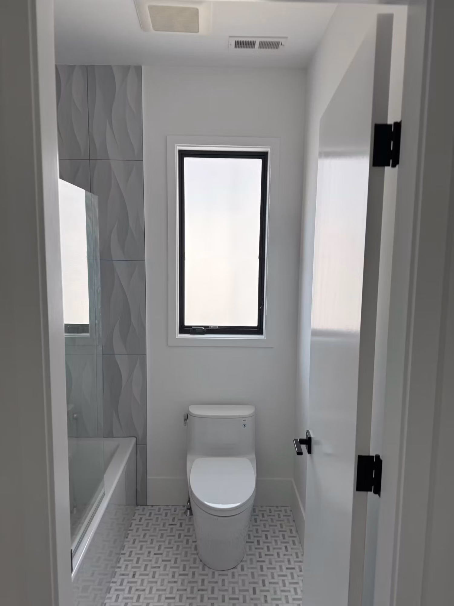 Small bathroom window above the toilet covered with white frosted privacy film for obscured glass.