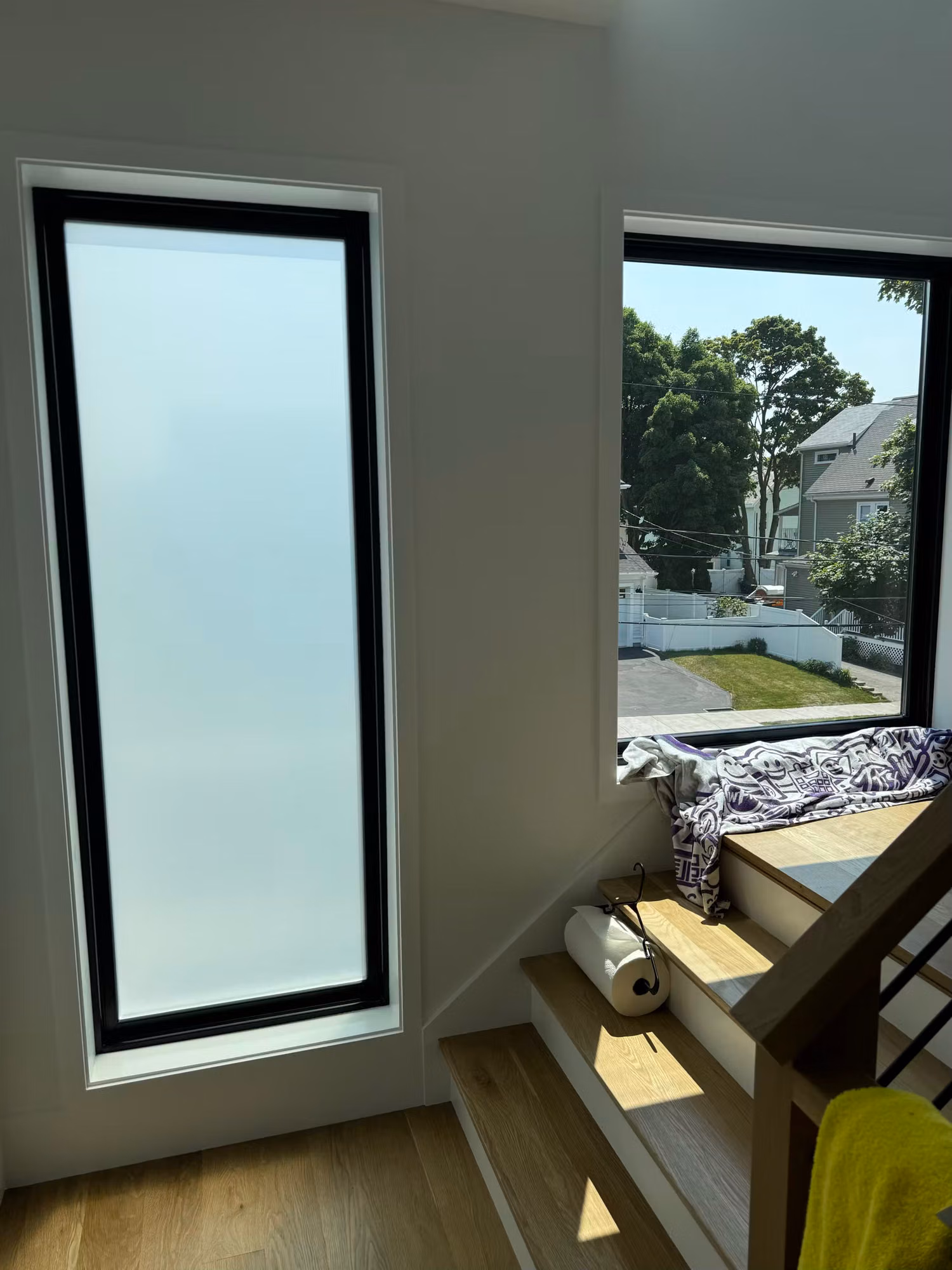 Tall frosted privacy window beside a clear window and built-in bench seat in a bright residential nook.