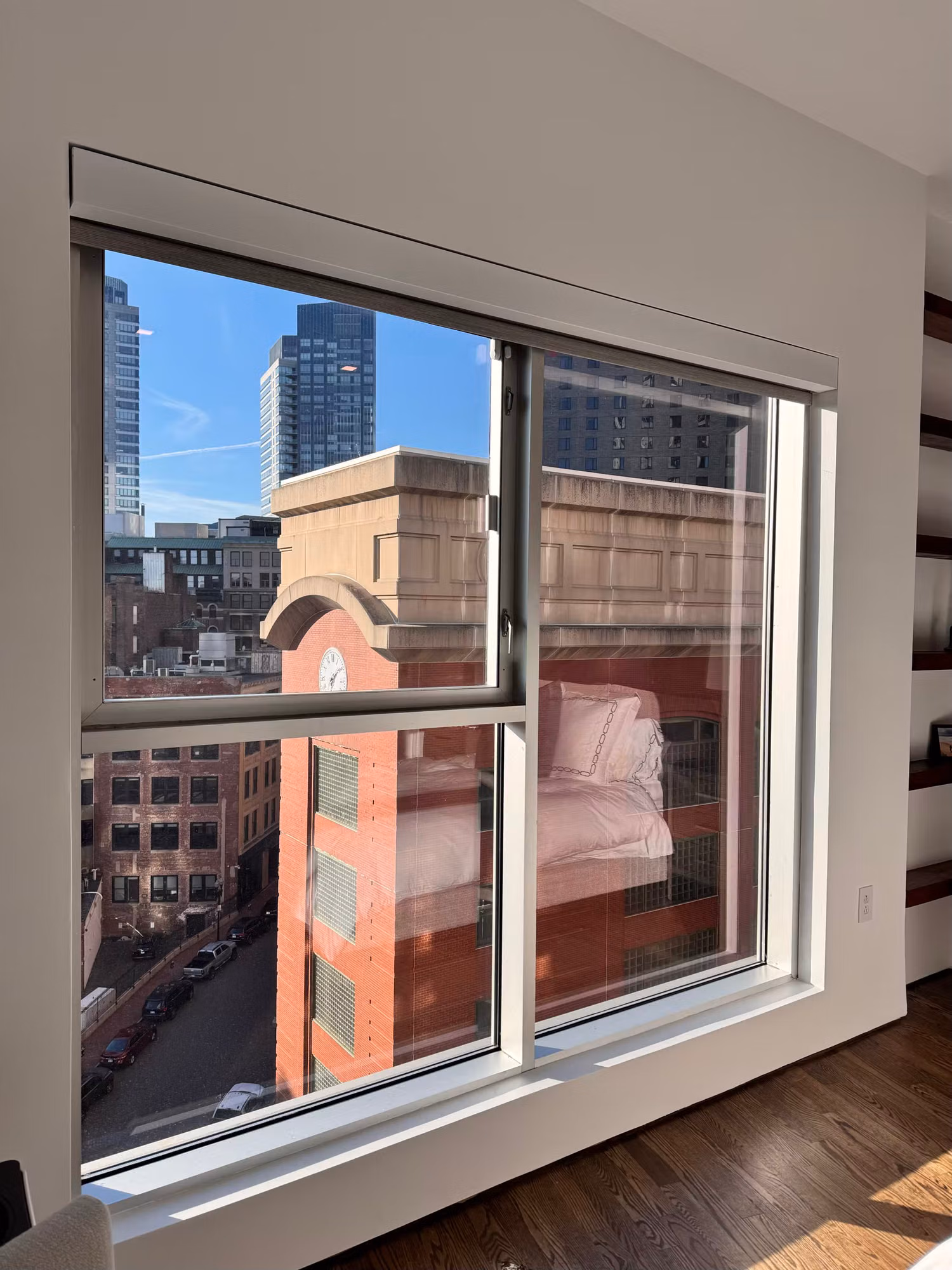 High-rise bedroom sliding window with clear solar control film and an unobstructed city skyline view.