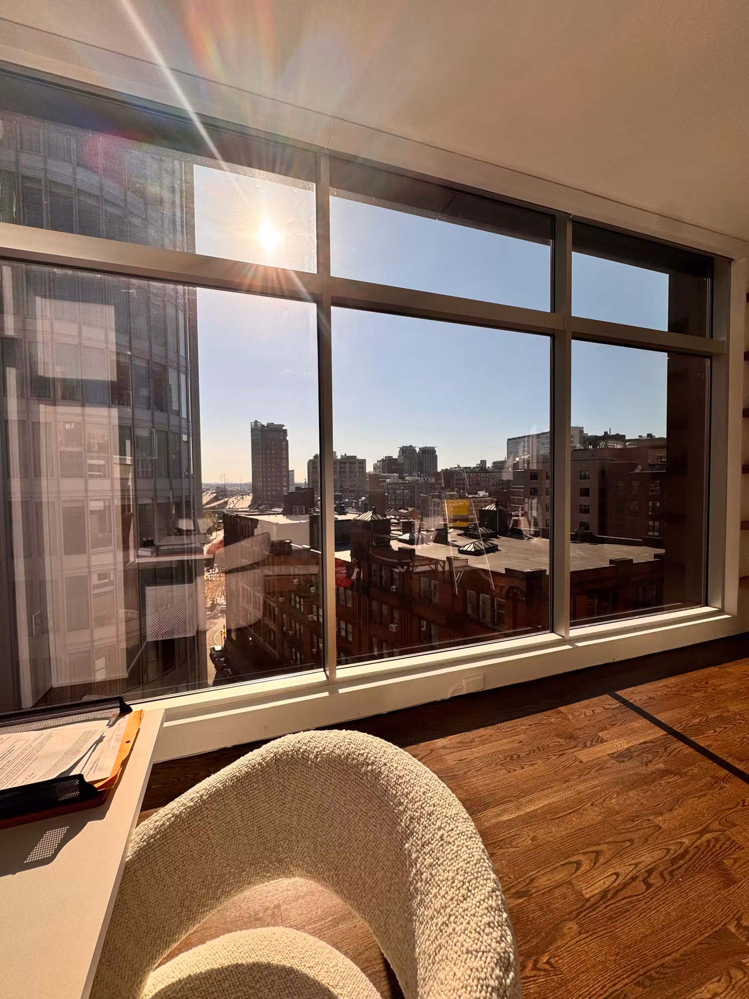 Corner floor-to-ceiling windows with solar film softening direct sunlight over a downtown skyline.