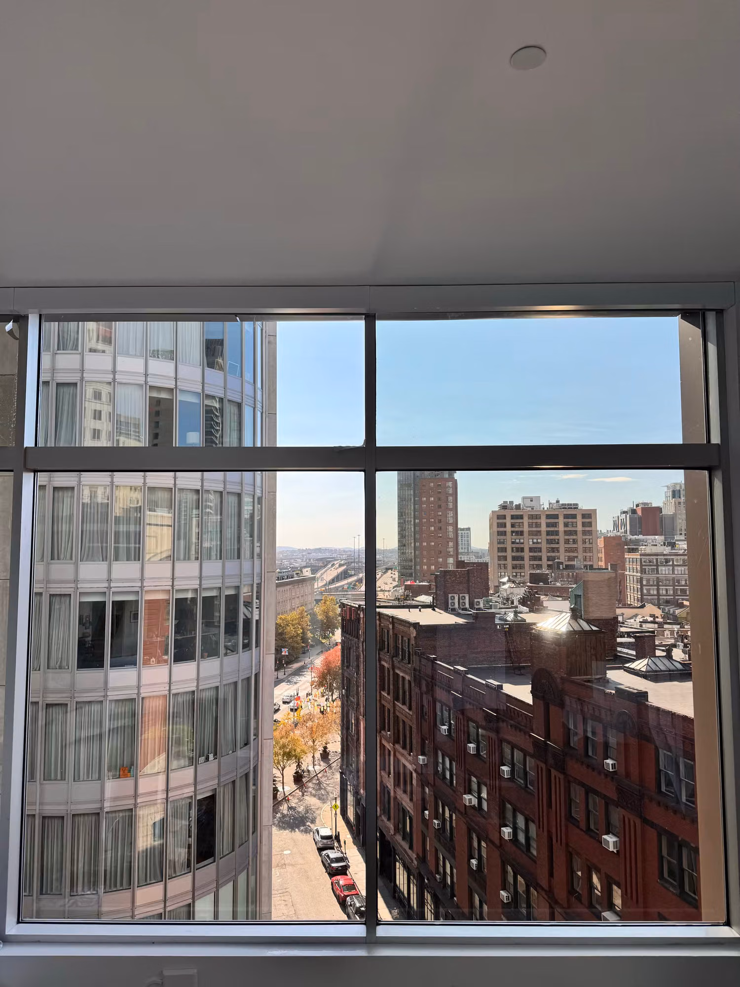 Tall corner picture window in an empty high-rise unit overlooking a city skyline with solar control film applied.