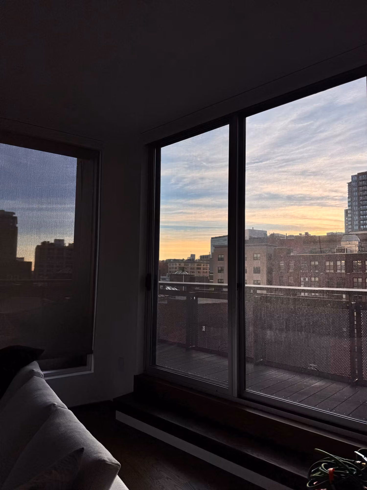 Living room corner floor-to-ceiling windows with solar control film framing a dusk city skyline.