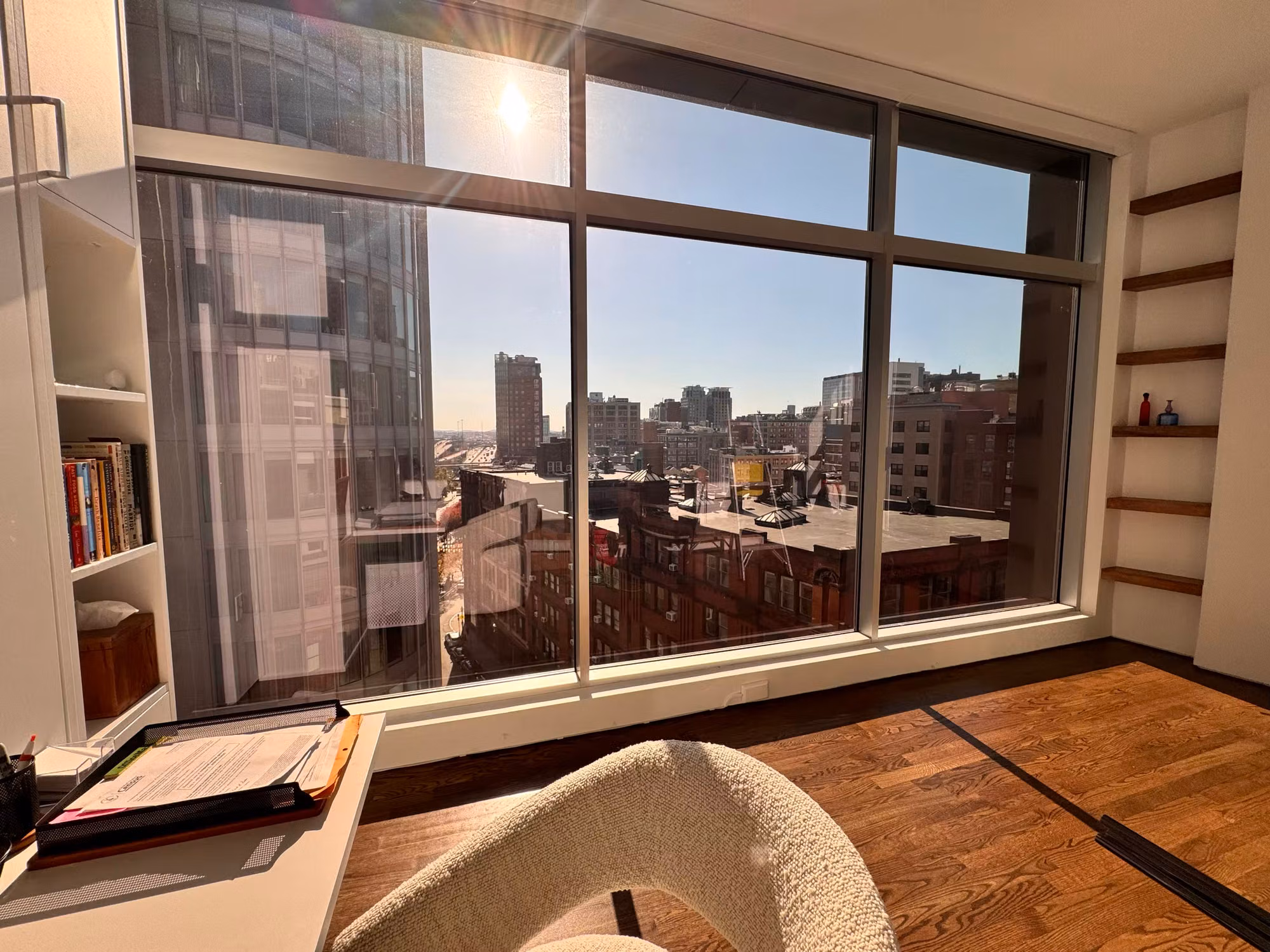 High-rise living area picture window with solar control film cutting glare on a sunlit city skyline view.