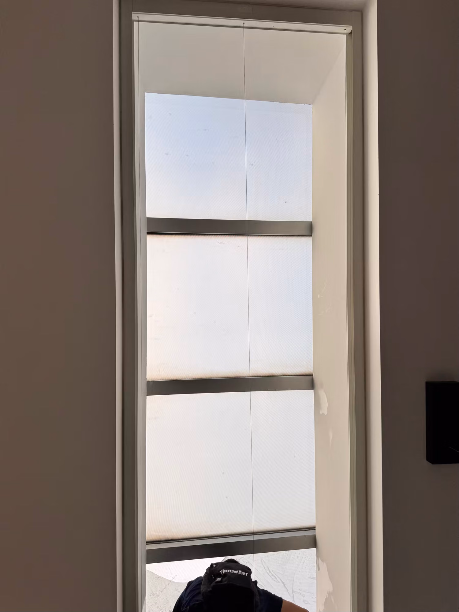 Tall slim window covered with frosted light-diffusing film that brightens the room while screening the view.