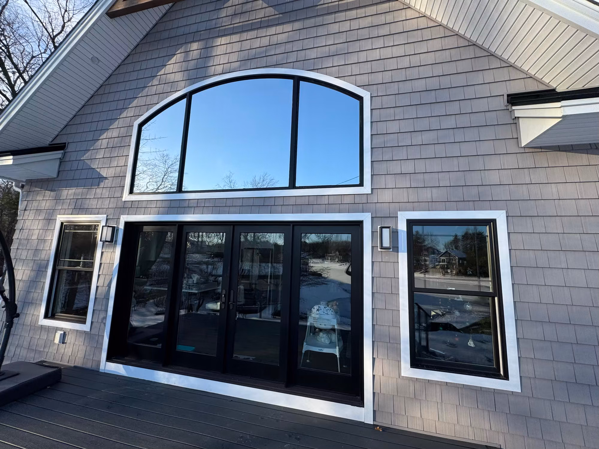 Reflective silver solar-control film on a home's arched transom window and sliding glass patio doors.
