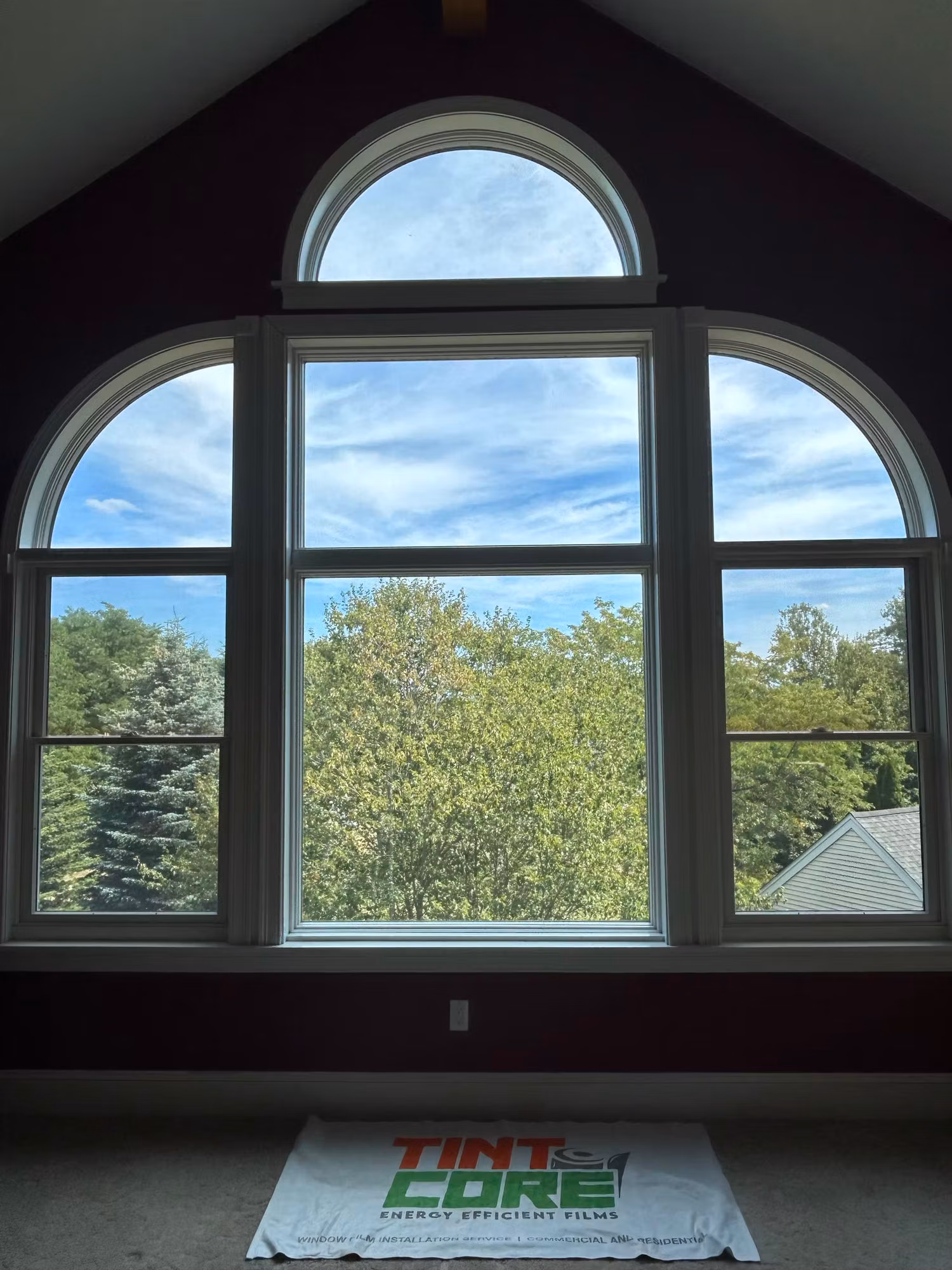 Large arched palladian window wall in a vaulted bedroom with clear film over the glass.