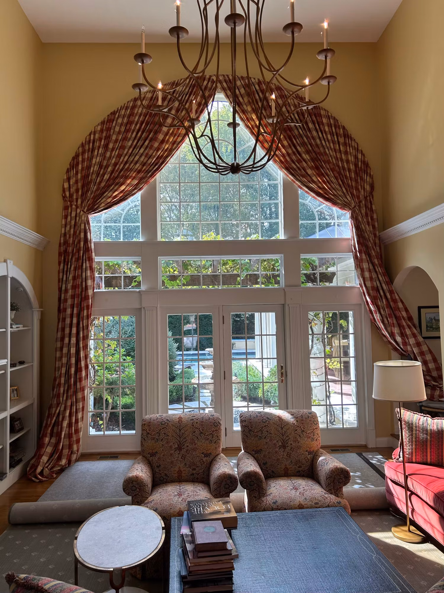 Two-story arched great room window above French doors framed by gingham drapery after window film install.