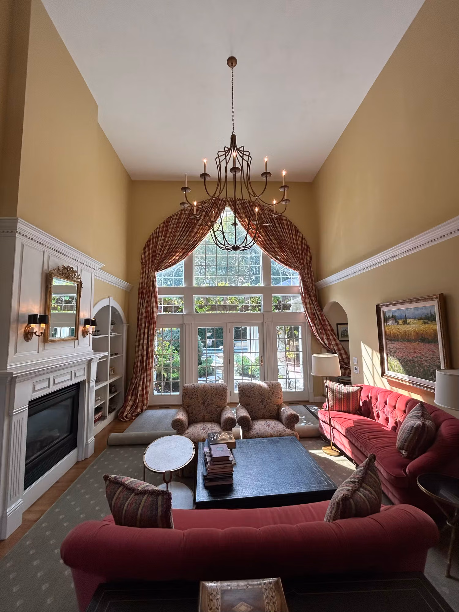 Sunlit double-height living room with a tall arched window and French doors treated with residential window film.