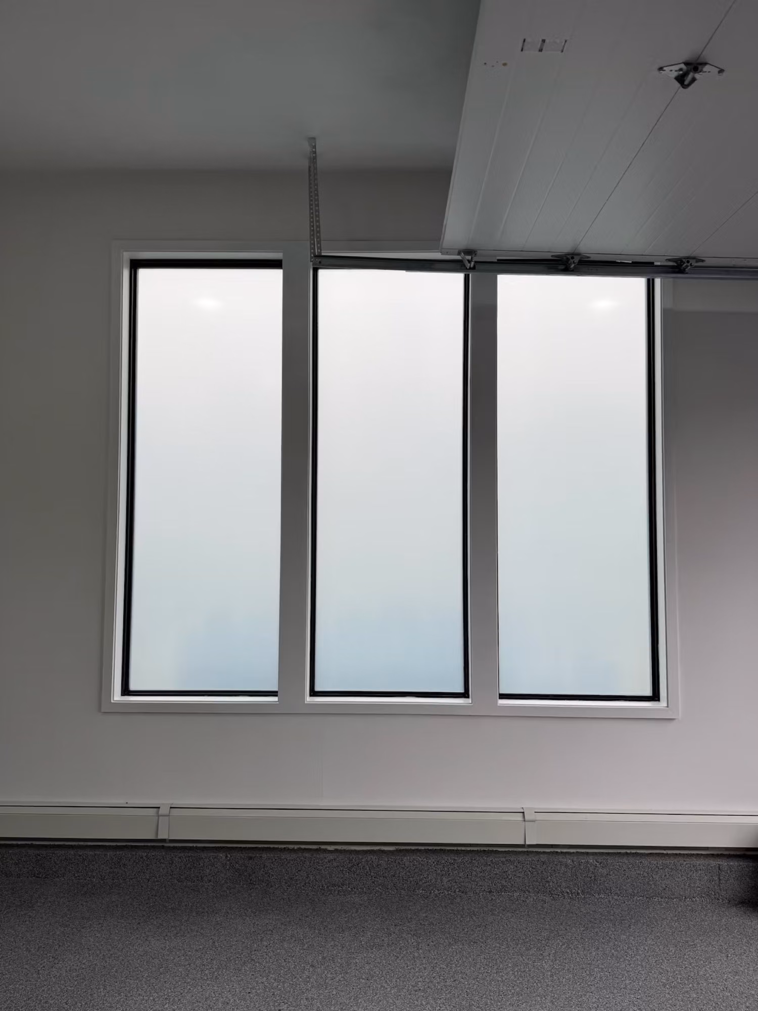Three tall windows finished with translucent frosted privacy film that softens light and obscures the view.