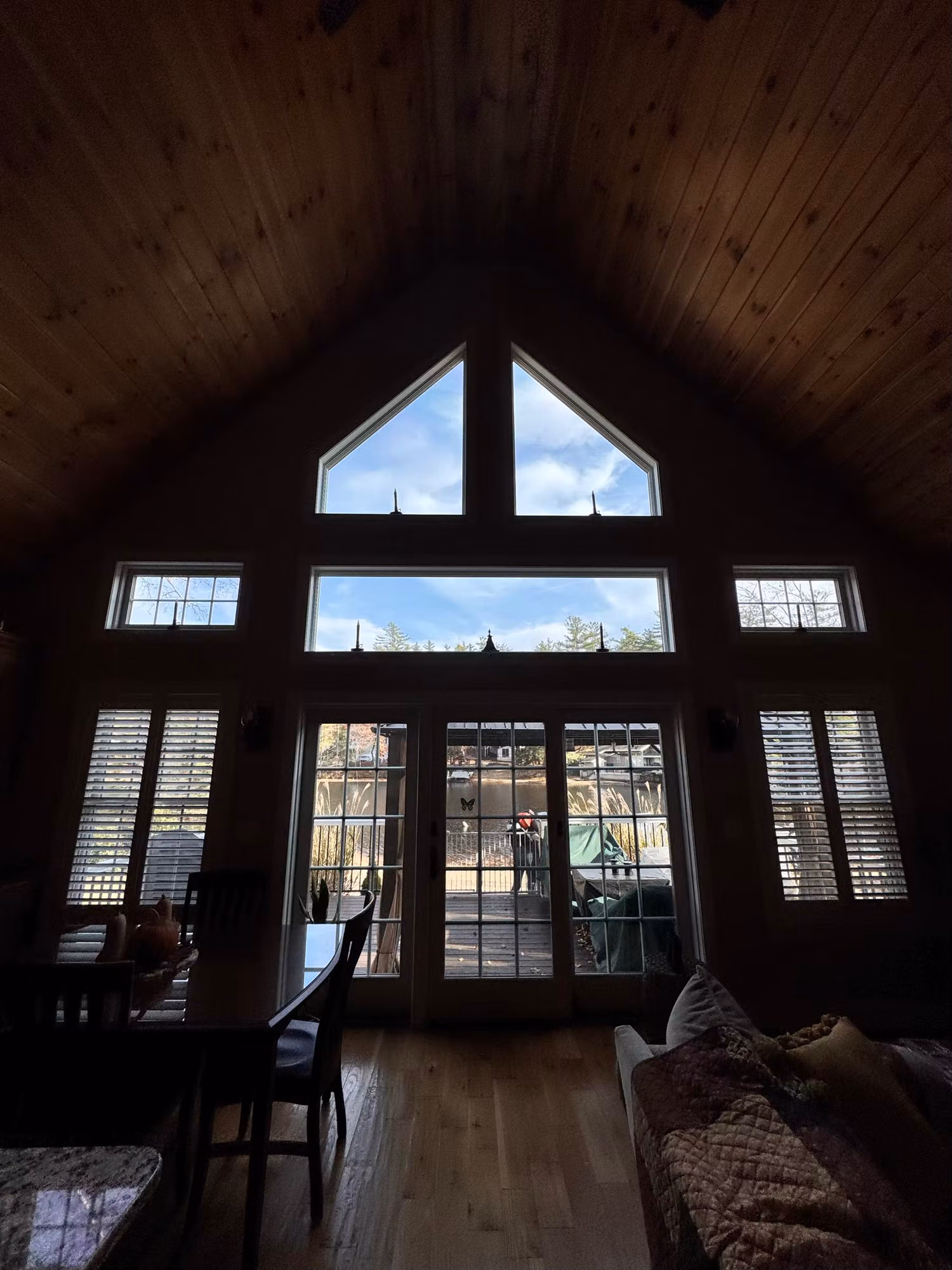 Vaulted great room with tall gable windows and French doors fitted with window film over the bright view.