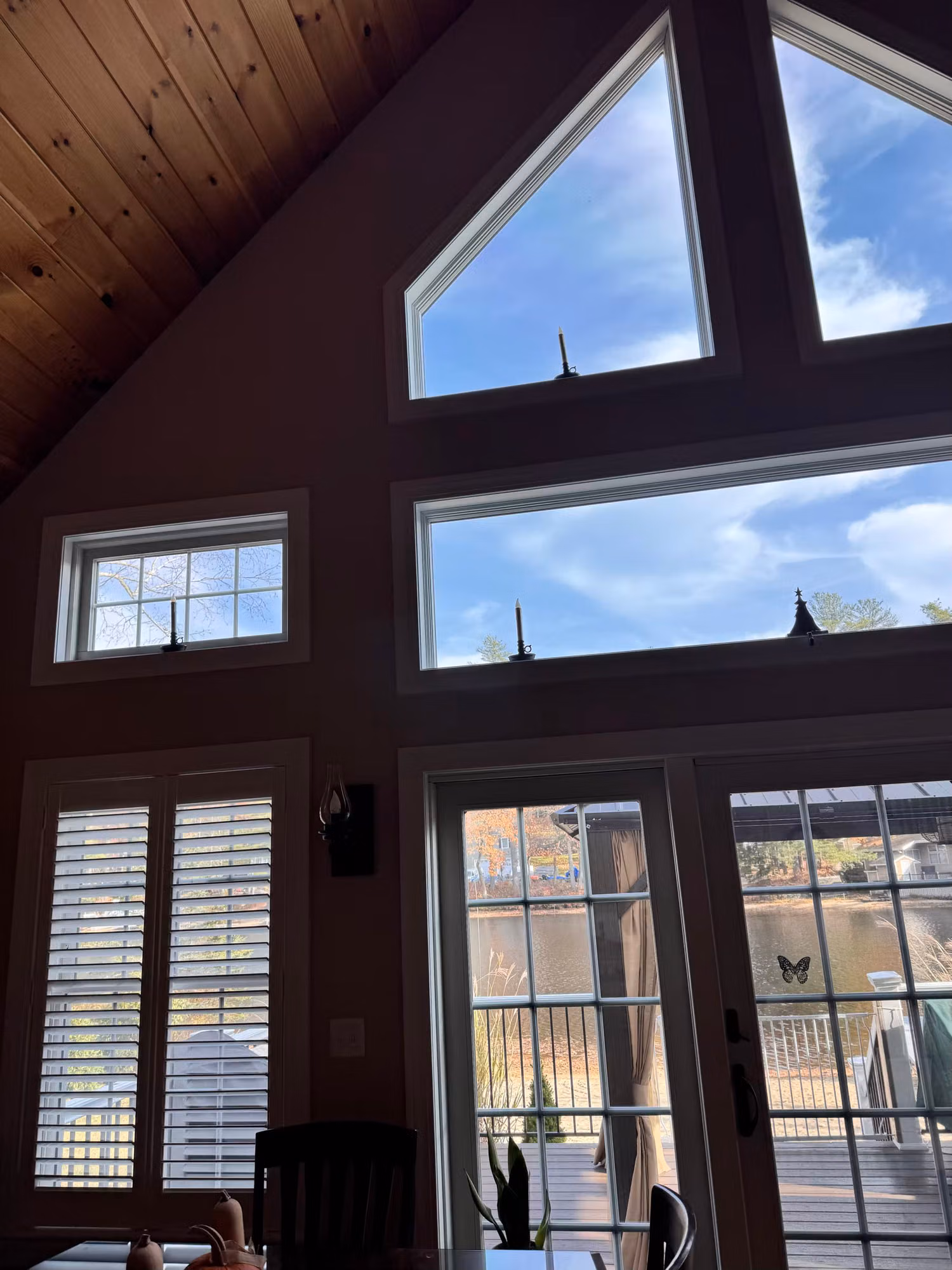 Triangular gable and transom windows over French doors with window film applied against the sunny sky.