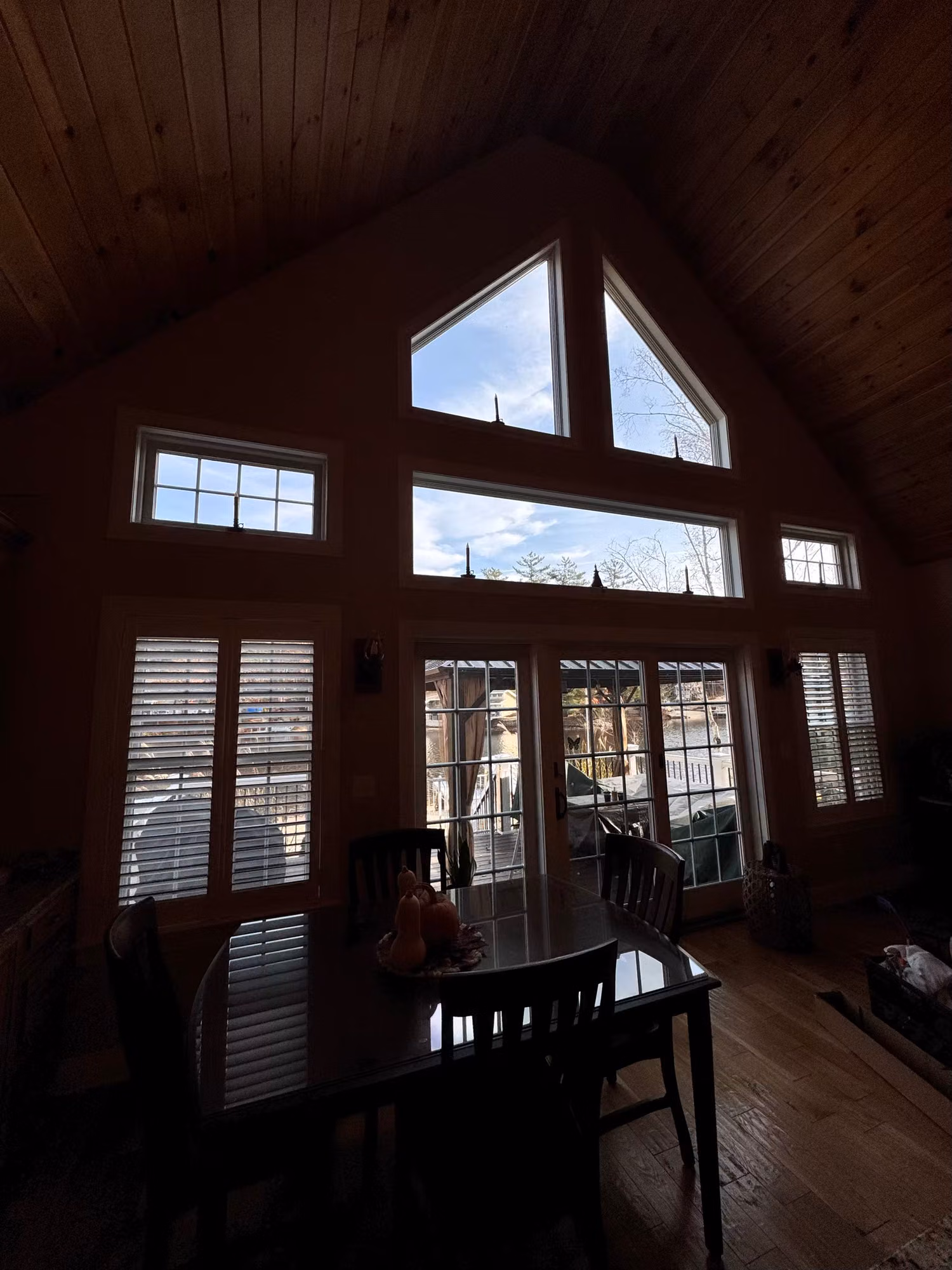 Vaulted dining room with a wall of gable windows and French doors fitted with window film.