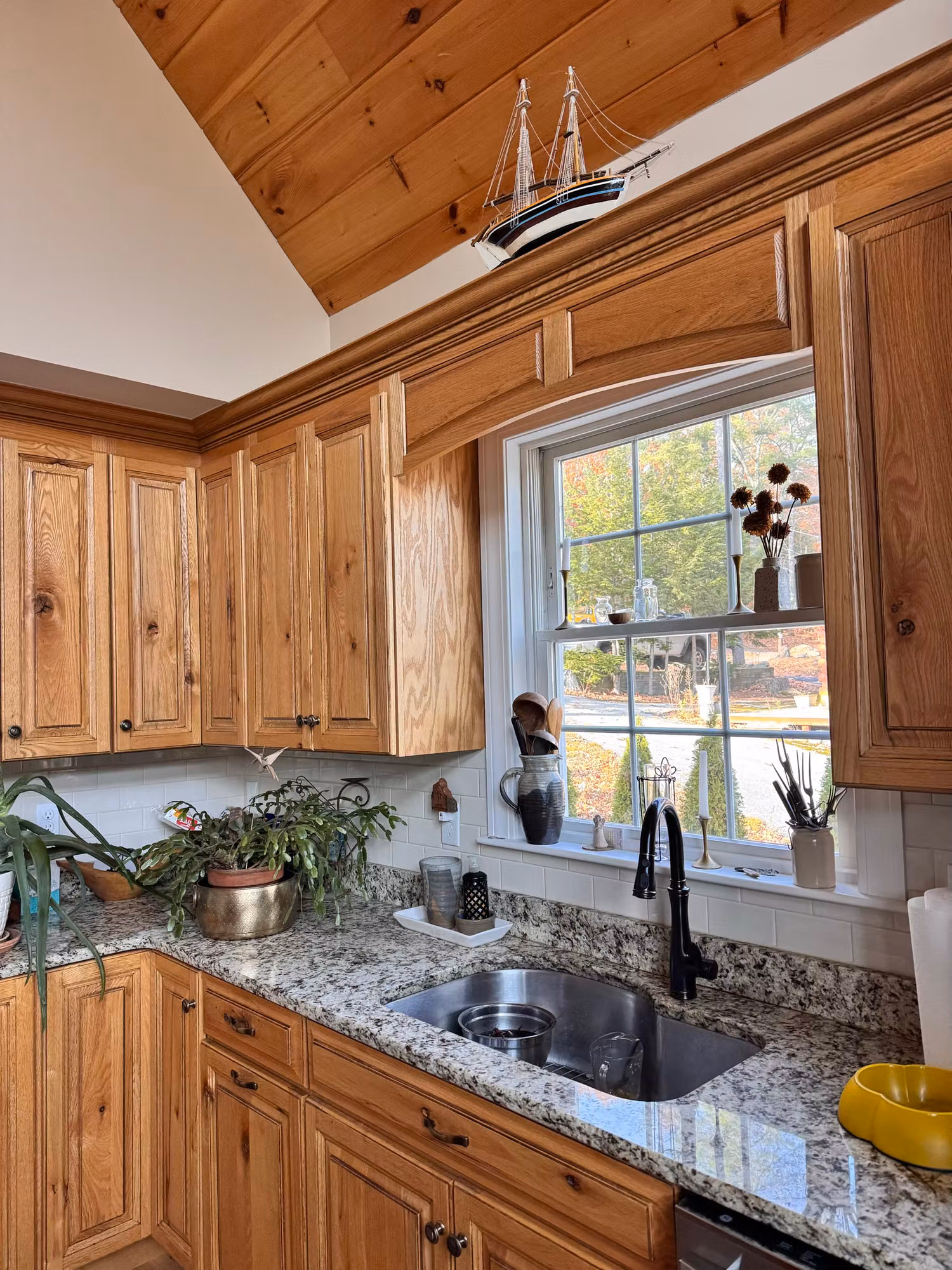 Wood-cabinet kitchen window above a granite counter and sink with window film applied to the glass.