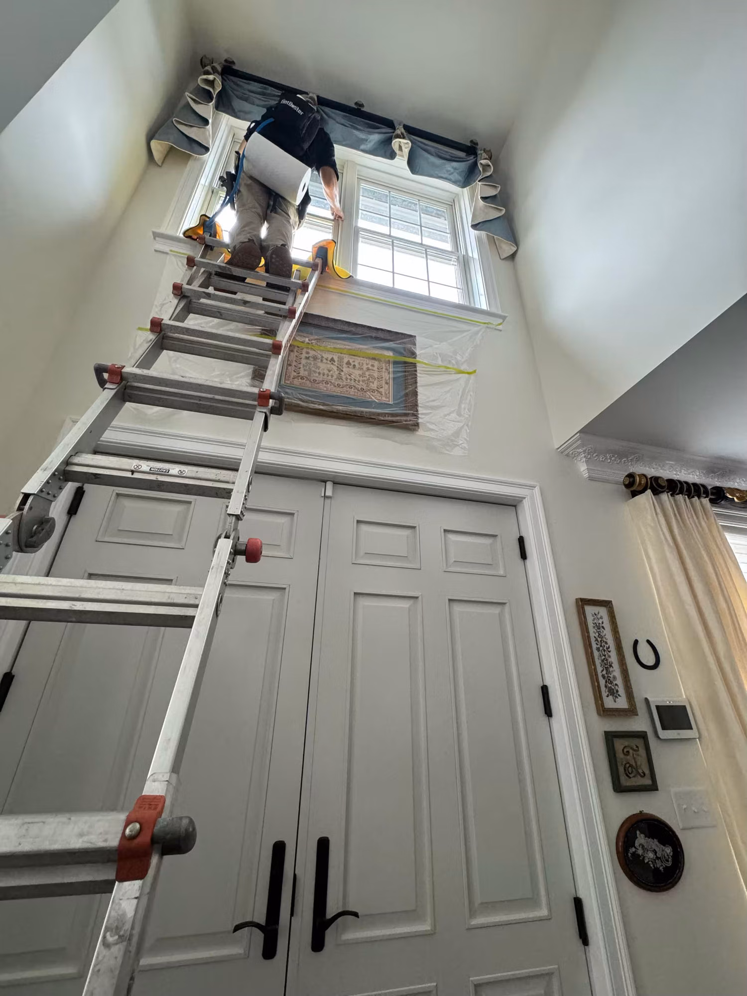Window film being applied to a tall foyer window above interior double doors during a residential install.